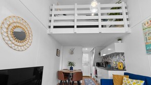 Un espace de vie compact comprenant un coin repas, un canapé, un téléviseur et un coin cuisine.