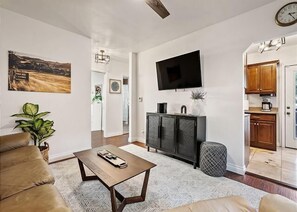 A living room with a sofa, coffee table, TV, and a plant.