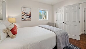 Ein Schlafzimmer mit Bett, Deckenventilator, Fenster und Tür.