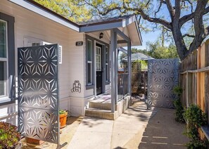 A house with a covered porch, a fenced yard, and a potted plant.