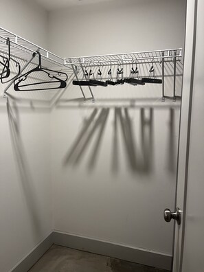 Spacious closet with a metal shelving unit for hanging clothes and a single door with a round handle.