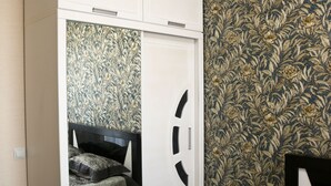 A bedroom with a wardrobe, a bed, and a patterned wallpaper. - Beautiful Apartment With Kind And Friendly Owners (tbilisi)