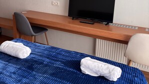 A hotel room with a bed, a desk, a chair, a television, and a radiator. - Beautiful Apartment With Kind And Friendly Owners (tbilisi)