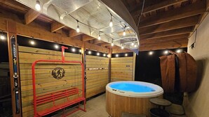 Ein Saunaraum mit Holzwänden, einer roten Sitzbank, einem Whirlpool und einem kleinen Tisch.