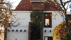 Un edificio con techo de ladrillo y paredes blancas, que presenta una ventana pequeña y una puerta.
