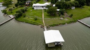 A riverside property with a dock, a large house with a porch, and a small shed. - Lakefront Property with a pool & hot tub! (Groesbeck)