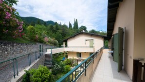 Ein Balkon mit Steinmauer, einem kleinen Garten und einem Gebäude mit grüner Tür.