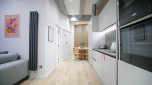 A modern kitchen with a built-in oven and a dining area with a table and chairs. - Chicago | The Heim (Manchester)
