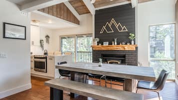 Une cuisine moderne dotée d’un grand îlot central, de poutres apparentes en bois au plafond et d’une cheminée.