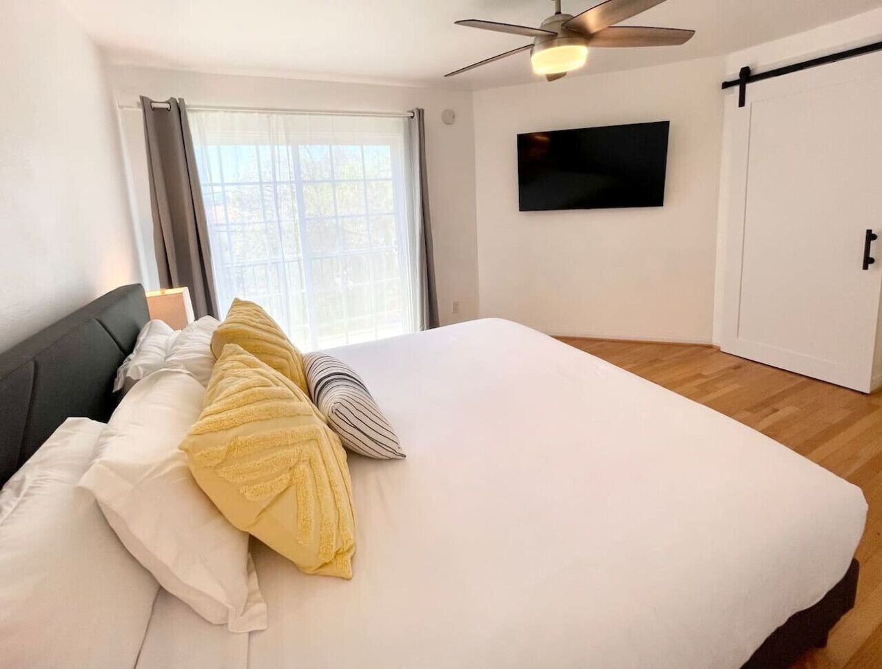 Un dormitorio con cama, ventilador de techo, televisor y armario.