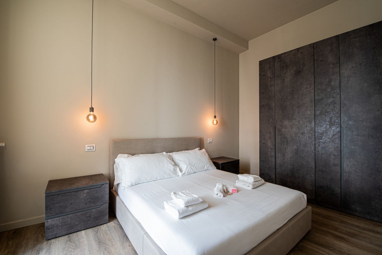 Ein modernes Schlafzimmer mit einem großen Bett, Nachttischen und einem Kleiderschrank.