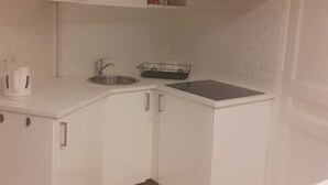 Une cuisine de taille réduite avec des meubles blancs, un évier et un plan de travail.