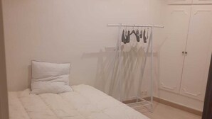 Une chambre à coucher avec un lit, une armoire et un étendoir.