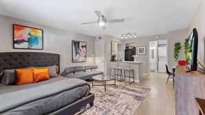 Um apartamento moderno com uma cama grande, um sofá, uma área de jantar e uma cozinha.