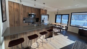 Una cocina moderna con armarios de madera, electrodomésticos de acero inoxidable y una isla grande con taburetes de bar.