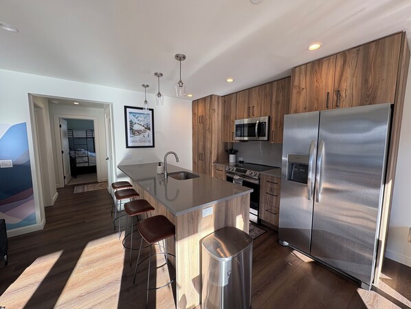 A modern kitchen with wooden cabinets, stainless steel appliances, and a central island with bar stools.