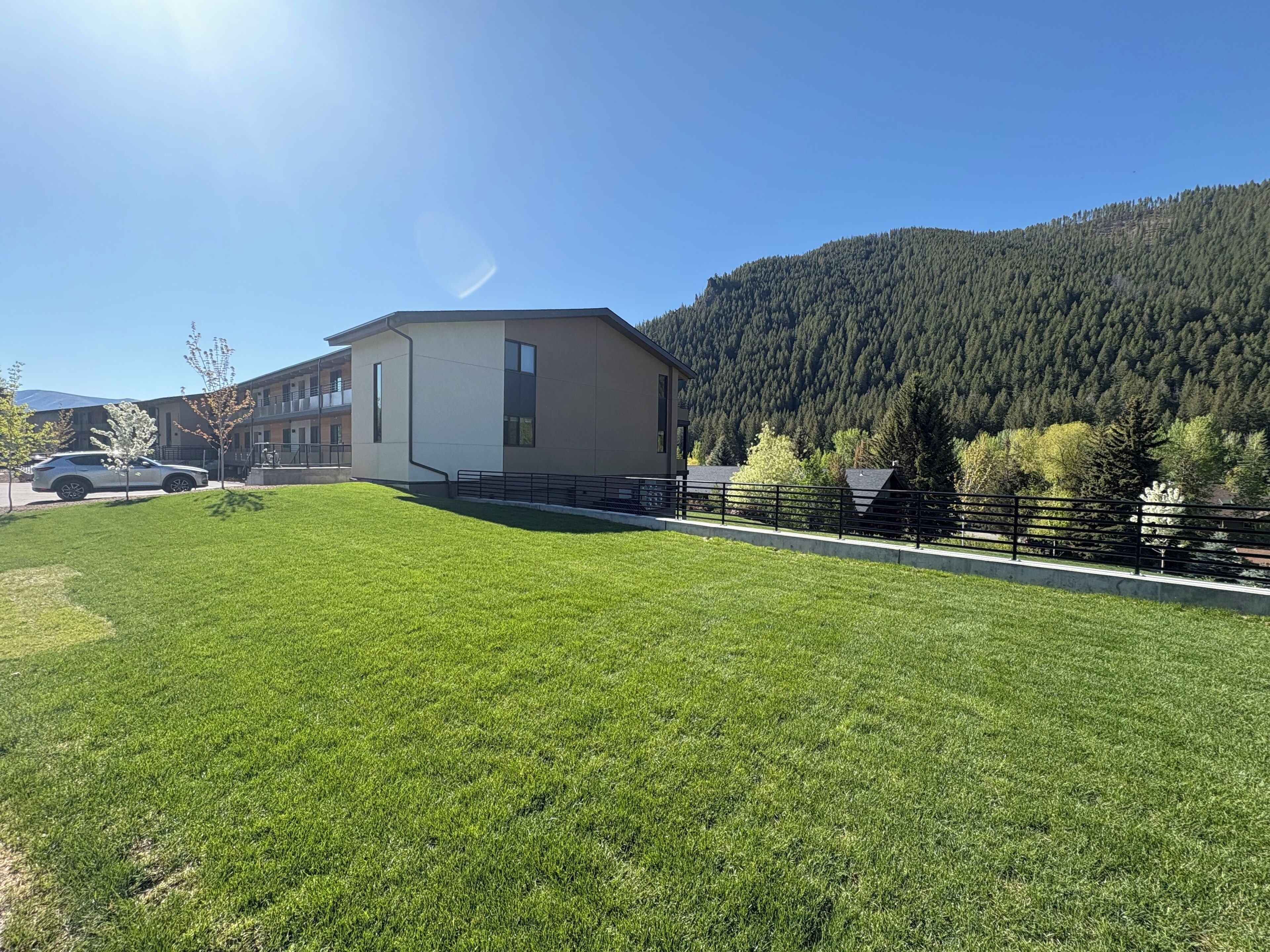 A modern building with a flat roof, a large window, and a paved driveway.