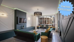 Ein modernes Wohnzimmer mit einer Couch, einem Hocker und einem an der Wand befestigten Fernseher.