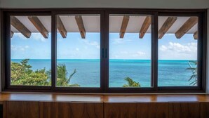 A room with a large window overlooking a turquoise sea and clear sky. - Villa Presidente | 4BR | Oceanfront Luxury Stay (Cancún)