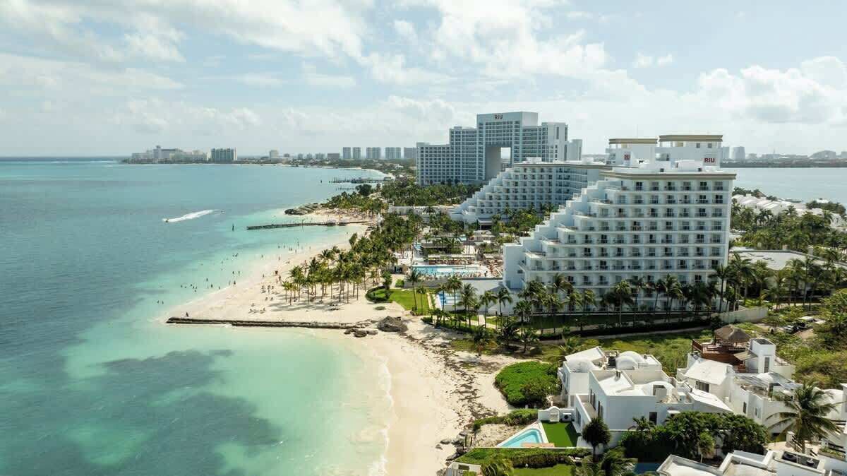 A coastal hotel with multiple buildings, a beach, and a clear view of the ocean.