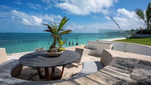 A round table with a potted plant, outdoor seating, and a view of the ocean. - Villa Presidente | 4BR | Oceanfront Luxury Stay (Cancún)