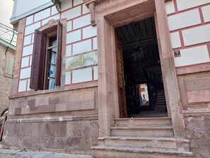 Step into the charming entrance of this traditional building, featuring a stone archway and a welcoming sign.