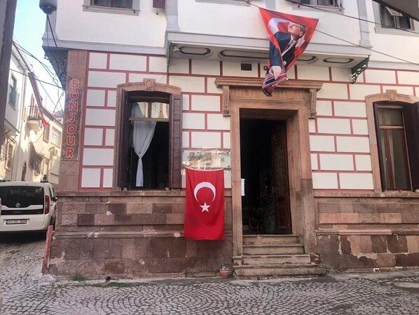 Experience the charm of a traditional Turkish building with a brick facade and wooden window frames, featuring a prominent flag and a welcoming entrance.