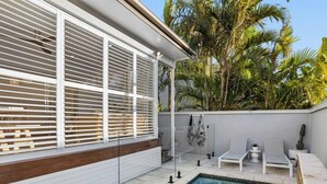 Ein moderner Poolbereich mit klarem Wasser, weißen Liegestühlen und einer Holzterrasse.