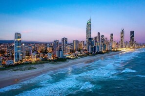 Un paisaje urbano costero con rascacielos, una playa y olas oceánicas.