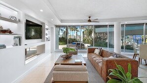 A modern living room with a large TV, comfortable seating, and a view of the outdoors. - Bnbbooking-Ocean view, Grd floor 4bd Condo,Pool,Spa (Surfers Paradise)