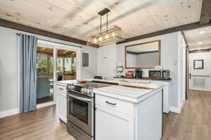 Une cuisine moderne dotée d’un îlot central, d’un four encastré et d’un luminaire suspendu.