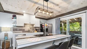 Una cocina moderna con una isla central, armarios blancos y vistas al exterior.