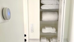 Un armario de acceso libre con estanterías blancas, un termostato y un interruptor de luz.