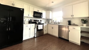 Una cocina moderna con armarios blancos, electrodomésticos de acero inoxidable y un refrigerador negro.