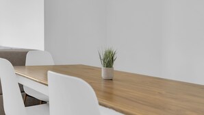 A dining table with a potted plant, white chairs, and a wooden table surface. - Steps from Perfection run.  (Beaverdell)