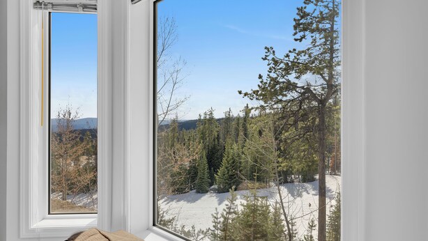A room with a large window overlooking a snowy landscape with trees and mountains. - Steps from Perfection run.  (Beaverdell)