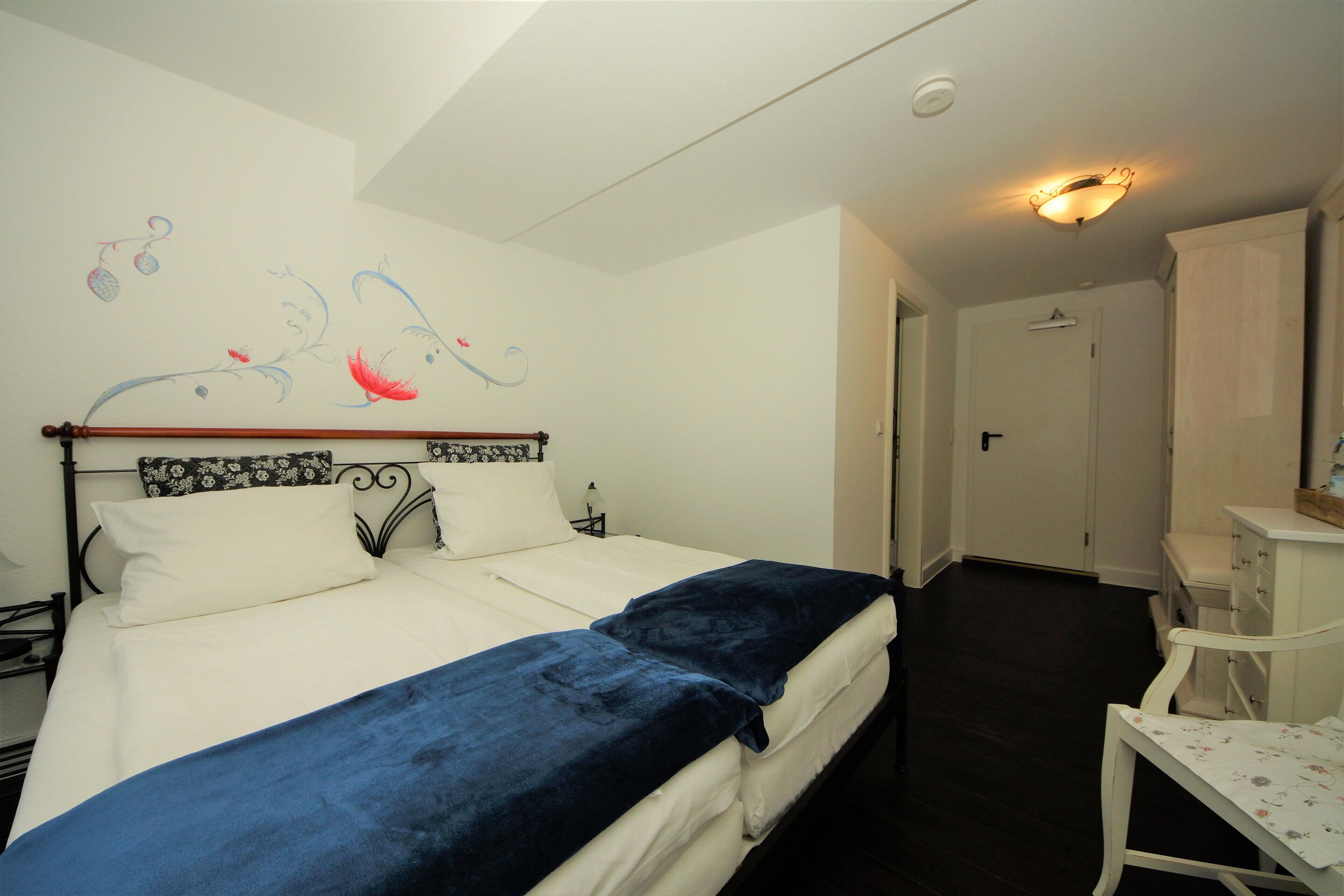 Ein Schlafzimmer mit einem Bett, einem Nachttisch, einer Kommode und einer Wand mit einem dekorativen Bild.