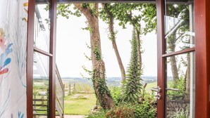 A doorway leading to a garden with a view of a landscape. - Polurrian House (Helston)