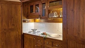 A rustic kitchen with wooden cabinets, a stone ceiling, and a tiled backsplash. - San Lorenzo (Verona)