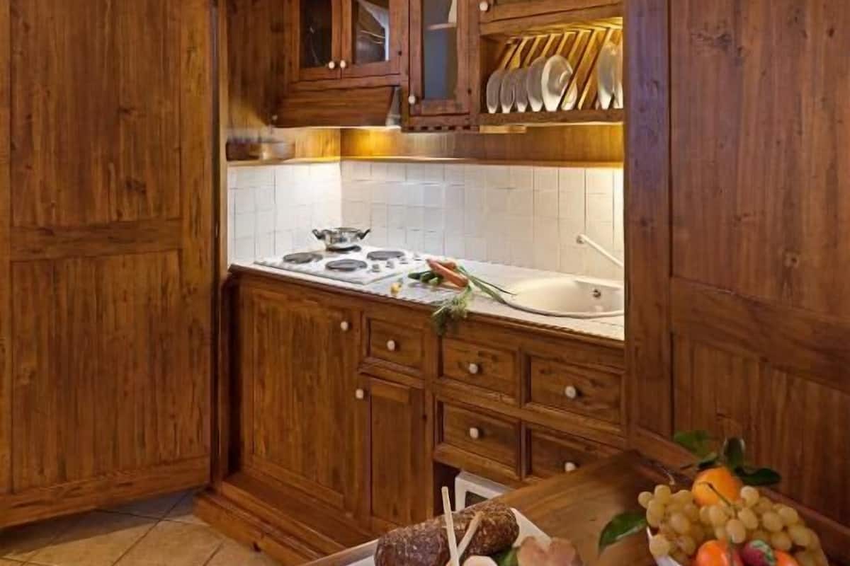 A rustic kitchen with wooden cabinets, a stone ceiling, and a tiled backsplash.