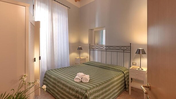 A bedroom with a bed, two bedside tables, a window, and a door. - San Lorenzo (Verona)
