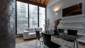 A modern dining area with a glass table, black chairs, and a sofa in the background. - San Lorenzo (Verona)