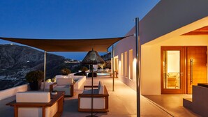 A modern outdoor seating area with a pool, overlooking a mountainous landscape. - Kamini White I Villa (Santorini)