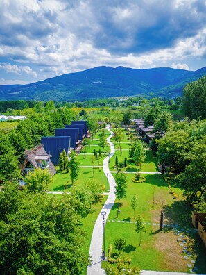 A landscaped area with a pathway, buildings, and mountains in the background.