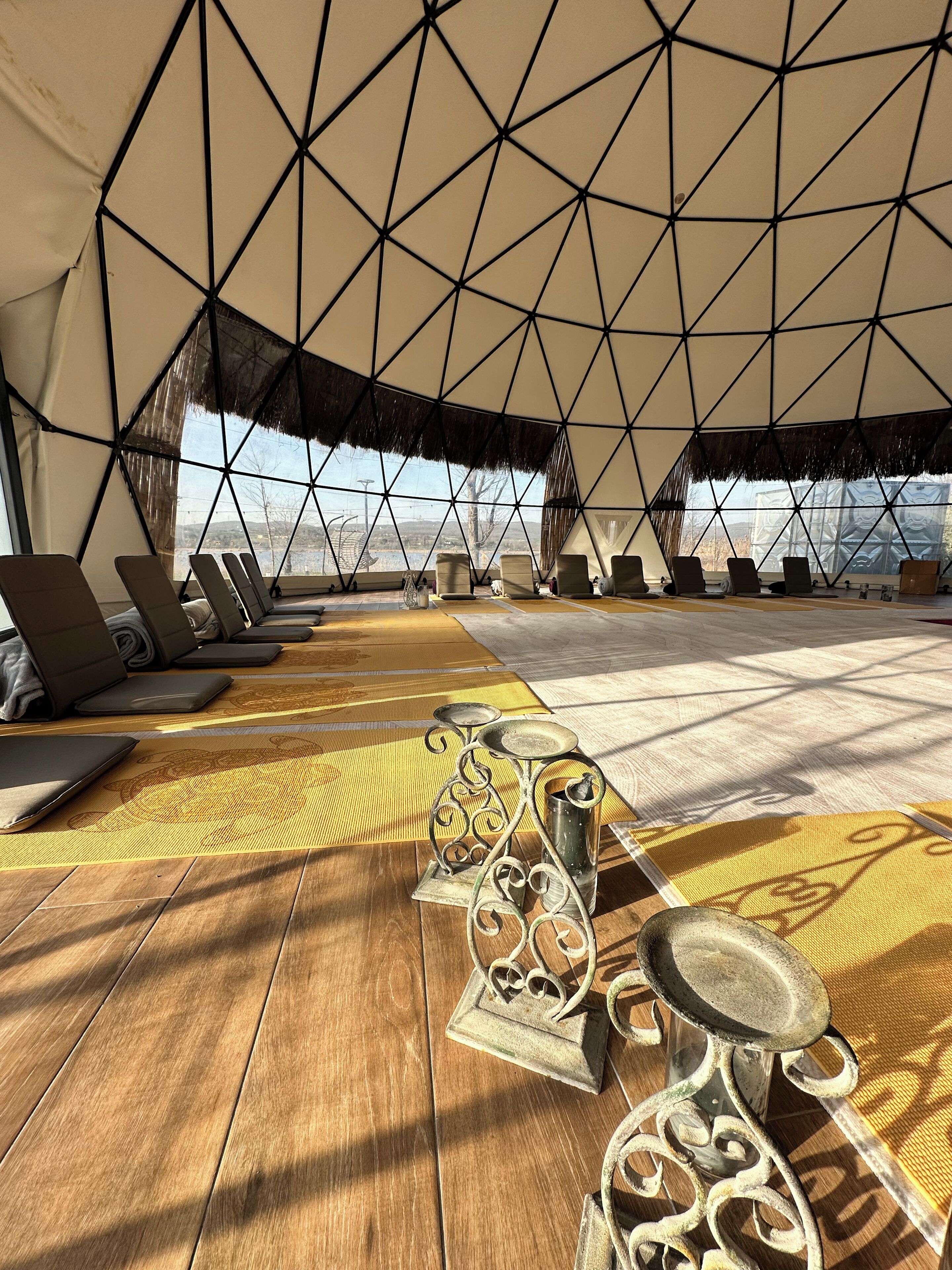 A geodesic dome structure with a wooden floor, lounge chairs, and a decorative metal table.