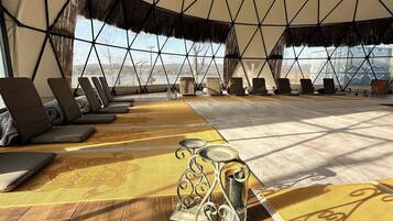 A geodesic dome structure with a wooden floor, lounge chairs, and a decorative metal table.