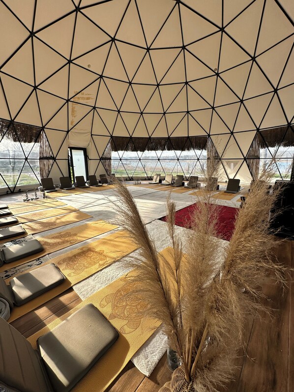 A geodesic dome interior with seating, a view of the outdoors, and a patterned floor.