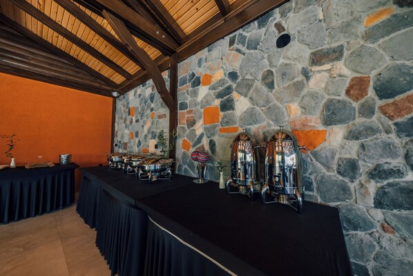A stone wall with a black table and silver appliances, likely for food service.