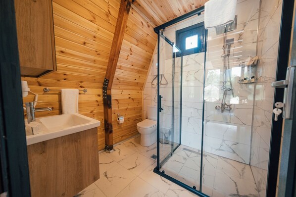 A wooden interior with a glass-enclosed shower, a sink, and a toilet.