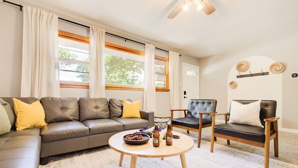 Un salon comprenant un canapé, deux fauteuils, une table basse et un ventilateur de plafond.